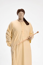 Cream Sudanese jalabiya with brown turban on a male mannequin against a white background, holding a cane